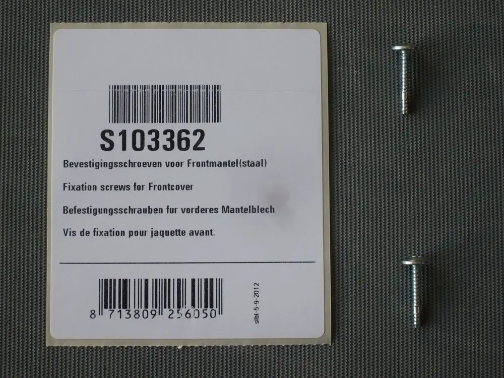 Zwei Befestigungsschrauben für einen Deckel, zusammen mit der passenden Produktinformation von Remeha.  
Die Schrauben sind neben dem Informationsetikett auf einer Oberfläche angeordnet.